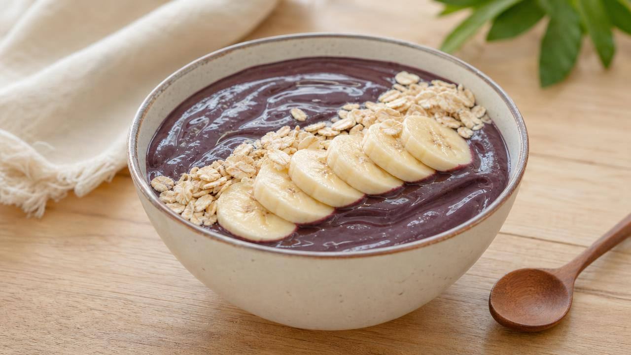 Tigela de açaí puro com banana e aveia em uma mesa clara, em composição limpa e editorial