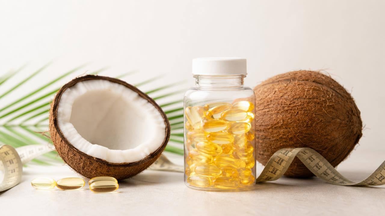 Frasco de cápsulas de óleo de coco ao lado de coco aberto e fita métrica, em composição limpa e profissional