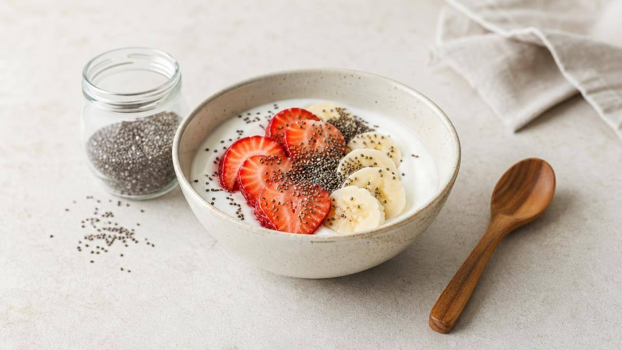 Tigela de iogurte natural com frutas frescas e sementes de chia sobre mesa clara