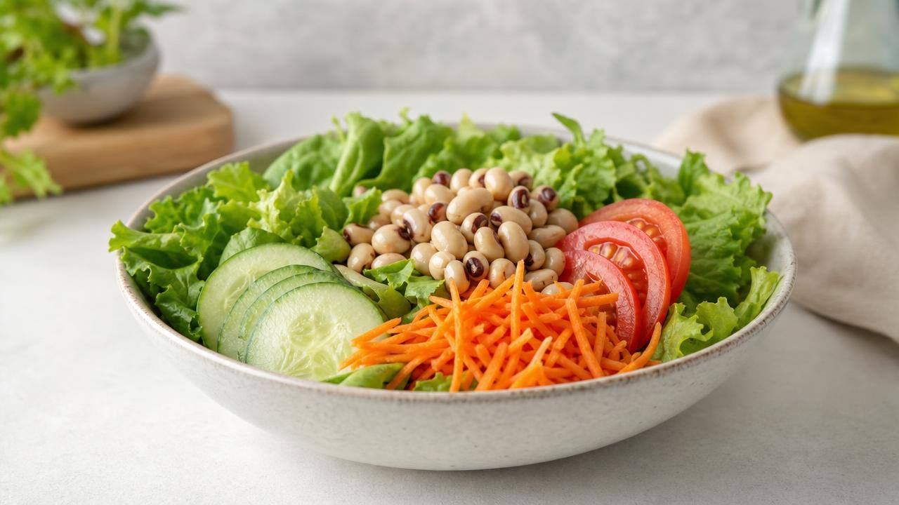 Salada colorida com folhas, tomate, cenoura e pepino servida como entrada em mesa clara