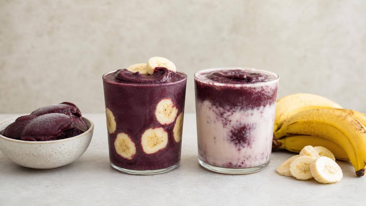 Copo de suco de açaí com banana ao lado de polpa de açaí e bananas frescas