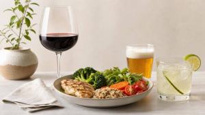 Ilustração de Taça de vinho, copo de cerveja e drink simples ao lado de alimentos frescos em mesa clara