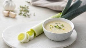 Ilustração de Alho-poró fresco cortado ao lado de uma sopa leve de legumes em mesa clara