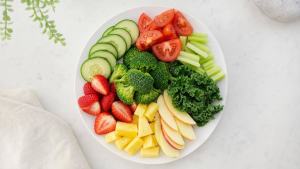 Ilustração de Prato com vegetais, frutas e folhas frescas em composição limpa e equilibrada