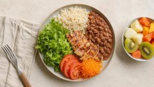 Ilustração de Prato equilibrado com feijão, arroz integral, salada, legumes e proteína em uma mesa clara