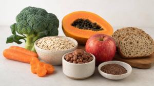 Tigela com aveia, feijão, frutas, legumes e sementes, representando alimentos ricos em fibras