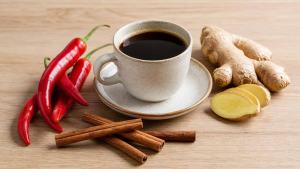 Café, pimenta vermelha, gengibre e canela organizados sobre uma mesa clara