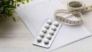 Ilustração de Cartela de comprimidos e receita médica ao lado de uma fita métrica, ilustrando o uso responsável de medicamentos no emagrecimento.