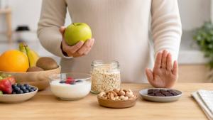 Pessoa organizando uma mesa com frutas, iogurte natural, aveia e pequena porção de chocolate, em ambiente claro e moderno