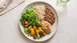 Ilustração de Prato equilibrado com legumes, feijão, arroz integral e proteínas, representando a redução consciente de carboidratos.