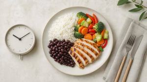 Ilustração de Prato equilibrado com arroz, feijão, salada e proteína ao lado de um relógio simples, representando a organização dos horários das refeições.
