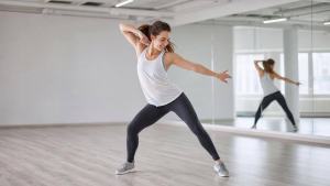 Pessoa praticando dança fitness em estúdio claro, com movimentos dinâmicos e ambiente profissional