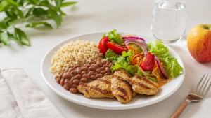 Prato equilibrado com arroz, feijão, frango grelhado, salada e fruta, representando um cardápio hipocalórico planejado