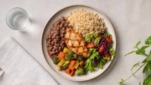 Ilustração de Prato equilibrado com arroz integral, feijão, legumes e salada em mesa clara