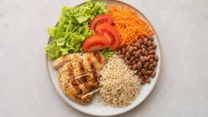 Prato equilibrado com alface, legumes, feijão, arroz integral e proteína, em composição limpa e profissional