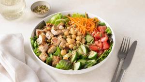 Salada completa com folhas, legumes, grãos e fonte de proteína em uma tigela branca