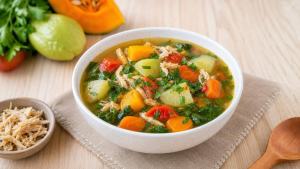 Tigela de sopa caseira com legumes, folhas e temperos naturais sobre mesa clara