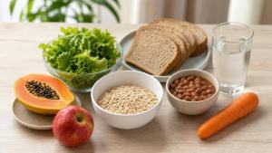 Mesa organizada com aveia, feijão, frutas, vegetais e pão integral, representando uma alimentação rica em fibras.