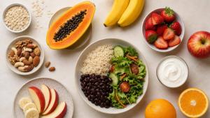 Frutas frescas, aveia, iogurte natural, castanhas e vegetais organizados sobre uma mesa clara para ilustrar um cardápio equilibrado