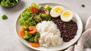 Ilustração de Ovo cozido acompanhado de vegetais, feijão e arroz em prato equilibrado