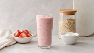 Copo de shake caseiro com fruta, aveia e iogurte sobre uma bancada clara