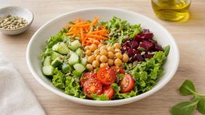 Salada colorida com folhas verdes, cenoura, pepino, tomate e grão-de-bico em uma tigela clara