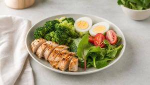 Prato equilibrado com fontes de proteína, legumes e verduras sobre mesa clara