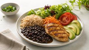 Prato equilibrado com arroz integral, feijão, legumes, folhas e proteína em mesa clara