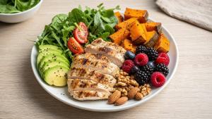 Ilustração de Prato equilibrado inspirado na dieta Paleo com frango, vegetais, abacate, frutas e castanhas