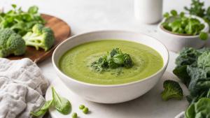 Tigela de sopa verde com legumes e folhas, servida de forma simples em uma mesa clara