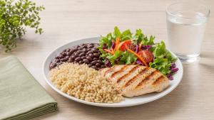 Ilustração de Prato equilibrado com arroz integral, feijão, frango grelhado, salada e legumes sobre mesa clara