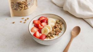 Ilustração de Tigela de iogurte natural com frutas frescas e pequena porção de granola em mesa clara