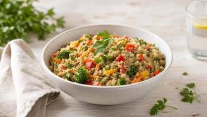 Tigela de quinoa cozida com legumes frescos em mesa clara, em composição editorial limpa