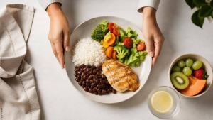 Ilustração de Pessoa organizando uma refeição equilibrada com arroz, feijão, legumes e frutas em uma mesa clara