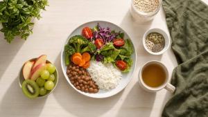 Mesa com chá, frutas, aveia e sementes ao lado de um prato de comida caseira equilibrada