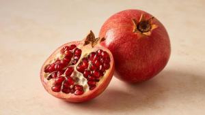 Romã aberta com sementes vermelhas em prato claro, em composição limpa e editorial