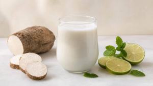 Copo de suco de inhame com limão ao lado de inhame cozido e frutas, em composição limpa e editorial