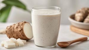 Copo de vitamina de inhame com leite ao lado de inhame cozido sobre mesa clara