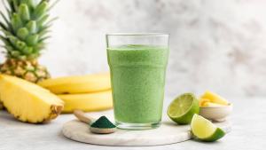 Ilustração de Copo de suco verde com spirulina, limão e frutas sobre bancada clara, em composição limpa e profissional
